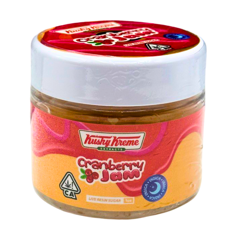 Jar of Kushy Kreme Cranberry Jam with a red lid on a white background